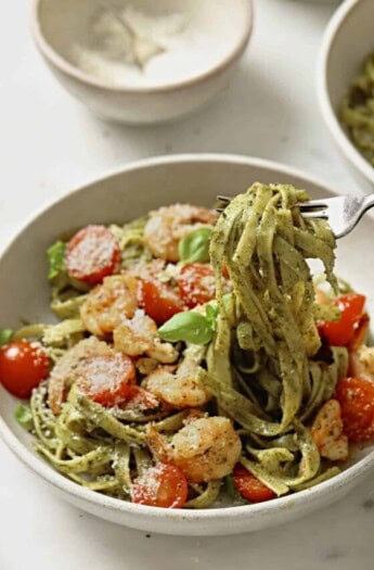 Picking up pesto fettuccine with a fork.