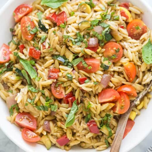 Bowl of orzo pasta salad with grilled veggies and balsamic dressing.