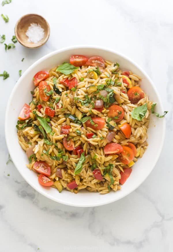 Bowl of orzo salad with grilled veggies and balsamic dressing.
