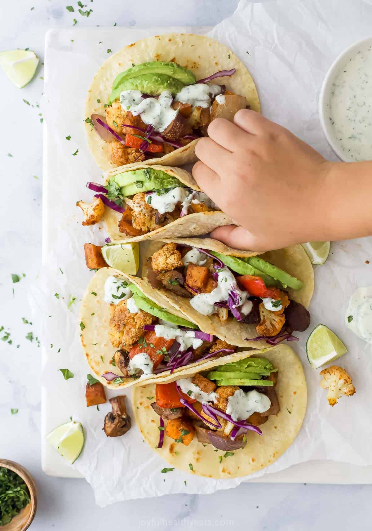 Avocado and red are catching a newly made taco with cabbage. 