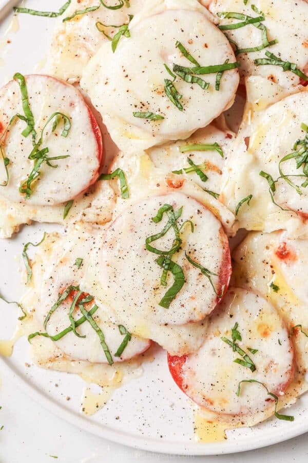 Close-up of the baked tomatoes of capress-style with fresh basil on top.