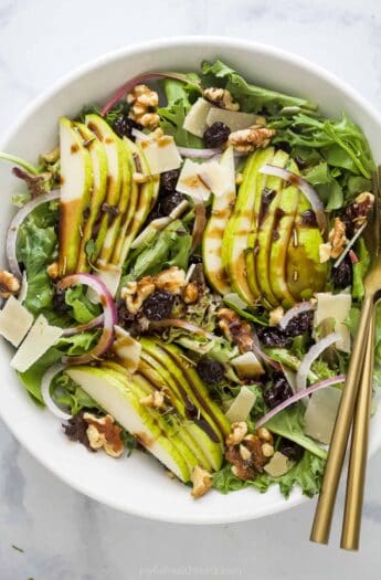 Large bowl of pear walnut salad with dried cherries and parmesan cheese.