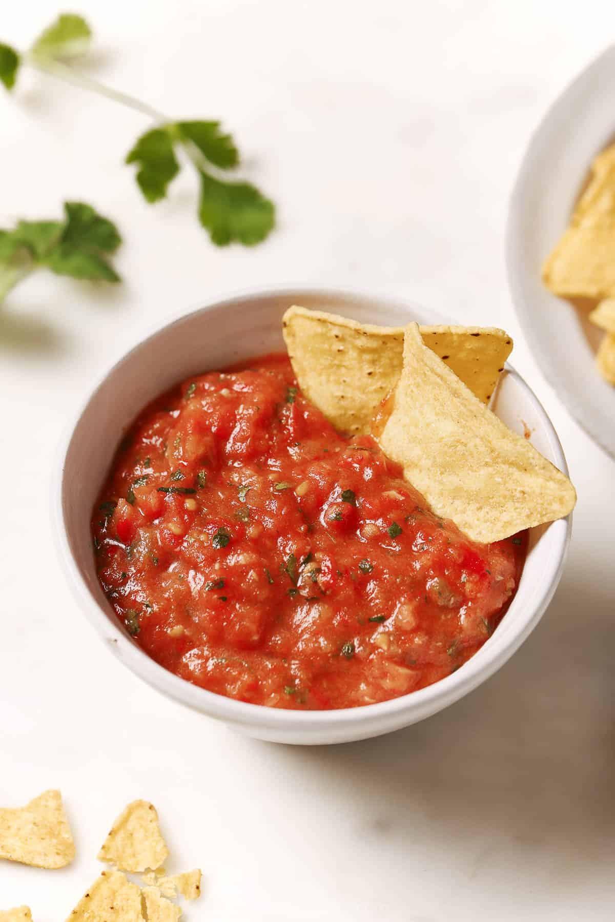 Roasted tomato salsa in a bowl with two tortilla chips. 