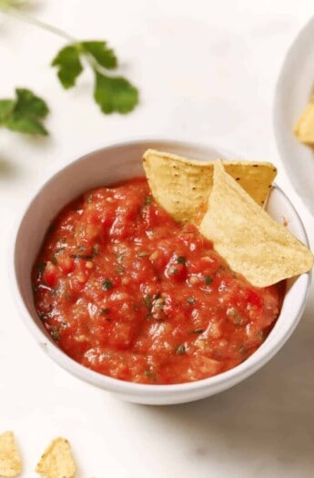 Roasted tomato salsa in a bowl with two tortilla chips.