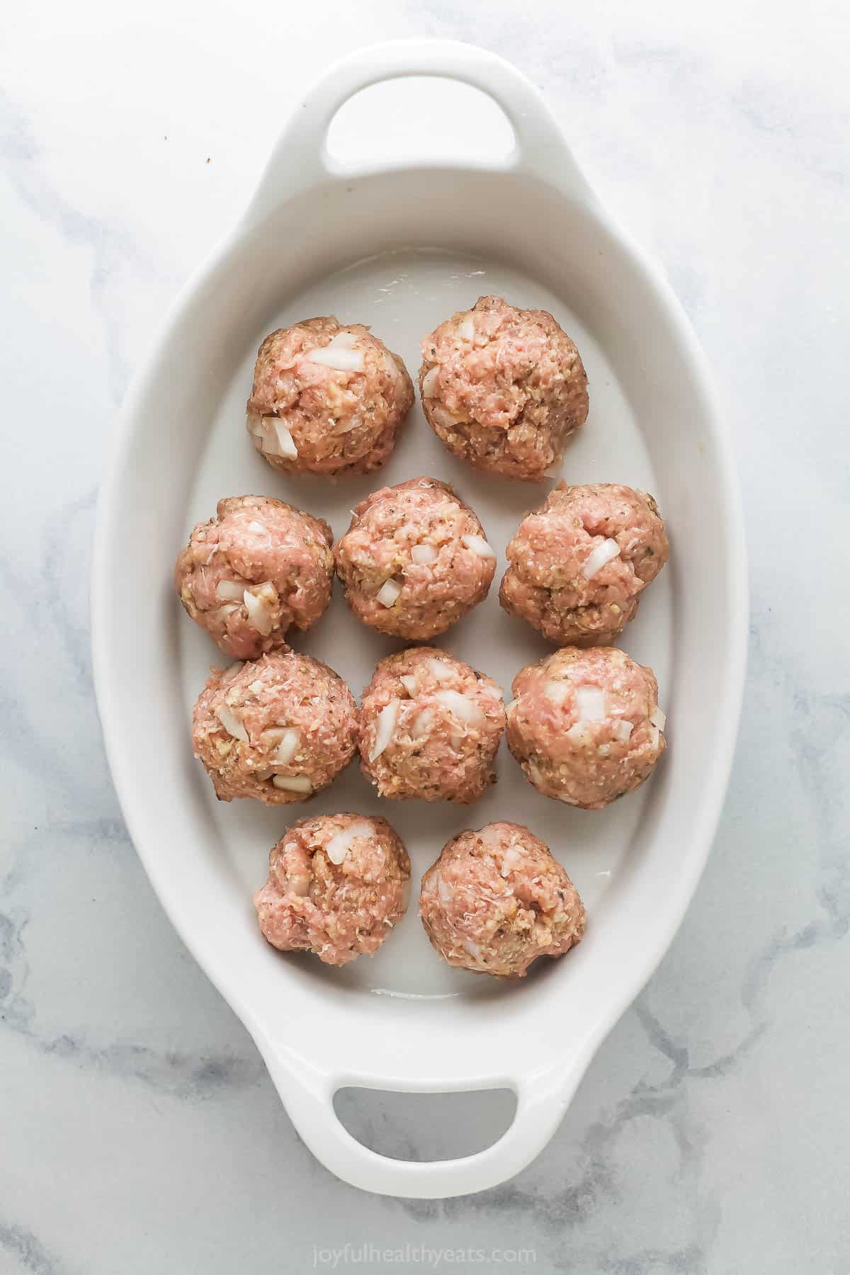 Raw meatballs in baking dish. 