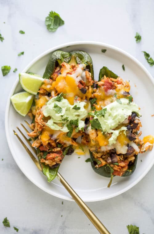 Plate of two stuffed poblano peppers with avocado crema.