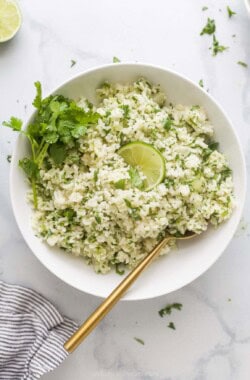 Large bowl of fluffy, homemade cilantro lime rice with fresh cilantro and a lime wedge as garnishes.