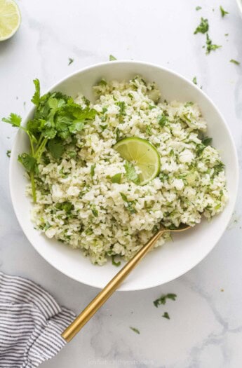 Large bowl of fluffy, homemade cilantro lime rice with fresh cilantro and a lime wedge as garnishes.