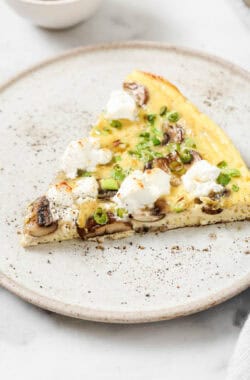 A slice of mushroom frittata with goat cheese and green onions.