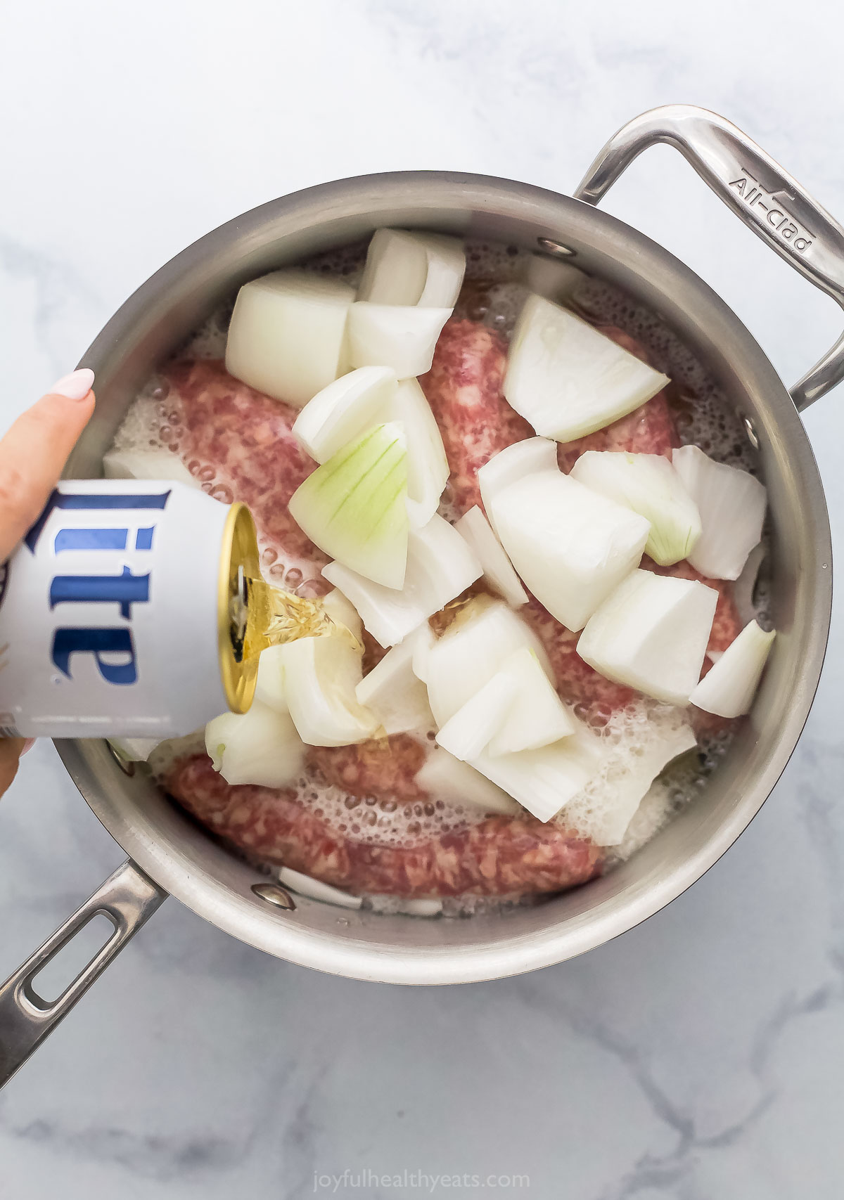 Adding the onions, beer, and sausages to the pot. 