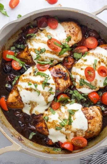 Skillet of caprese chicken with melty cheese.