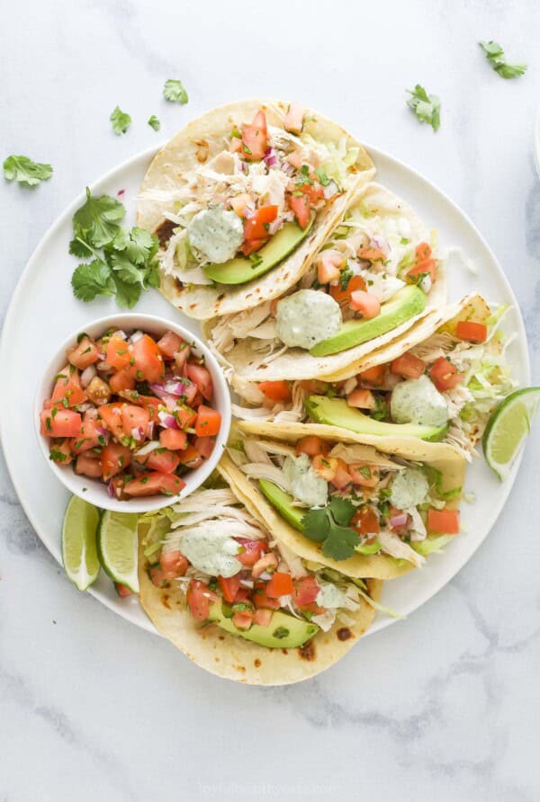 Assembled chicken tacos with a bowl of the onion-pepper mixture on the side.