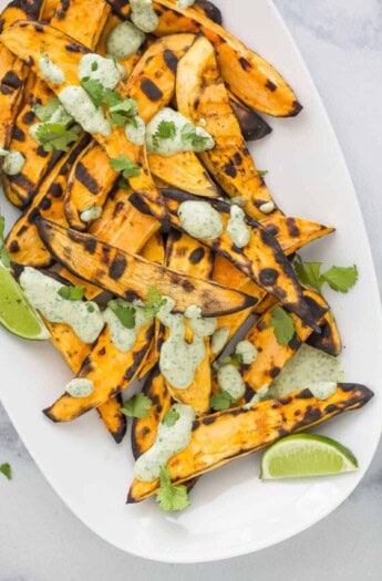 Plate of grilled sweet potatoes drizzled with lime cilantro crema.