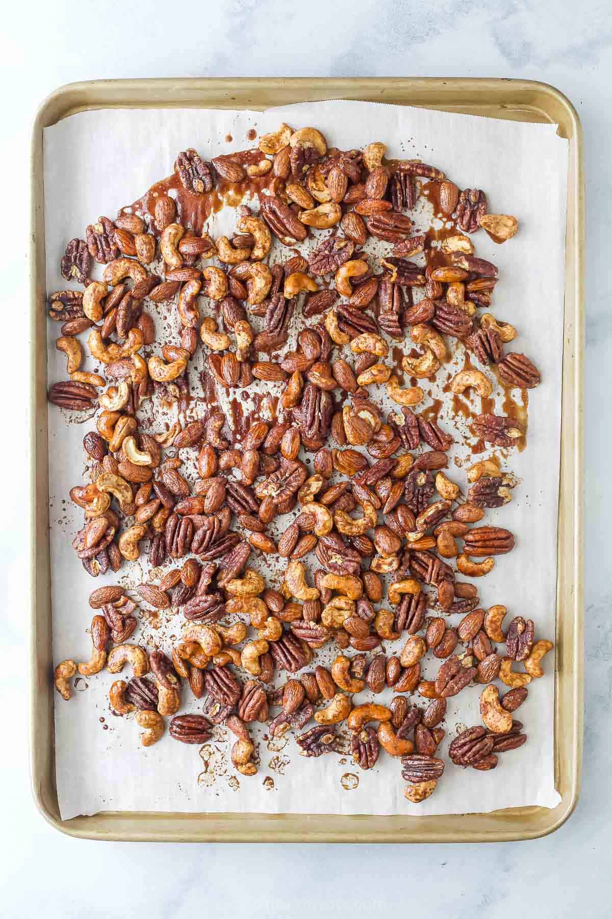 Baked nuts with spiced maple syrup on the baking sheet. 