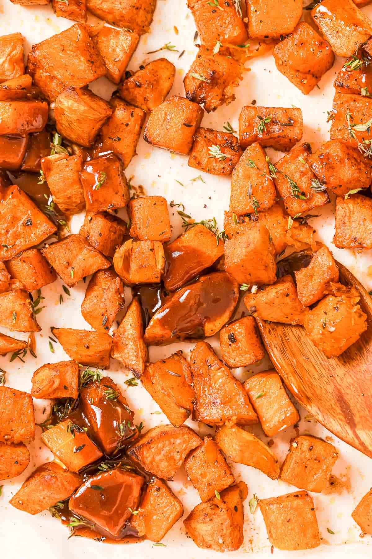 Close-up of diced, roasted sweet potatoes and squash with cinnamon butter on top. 