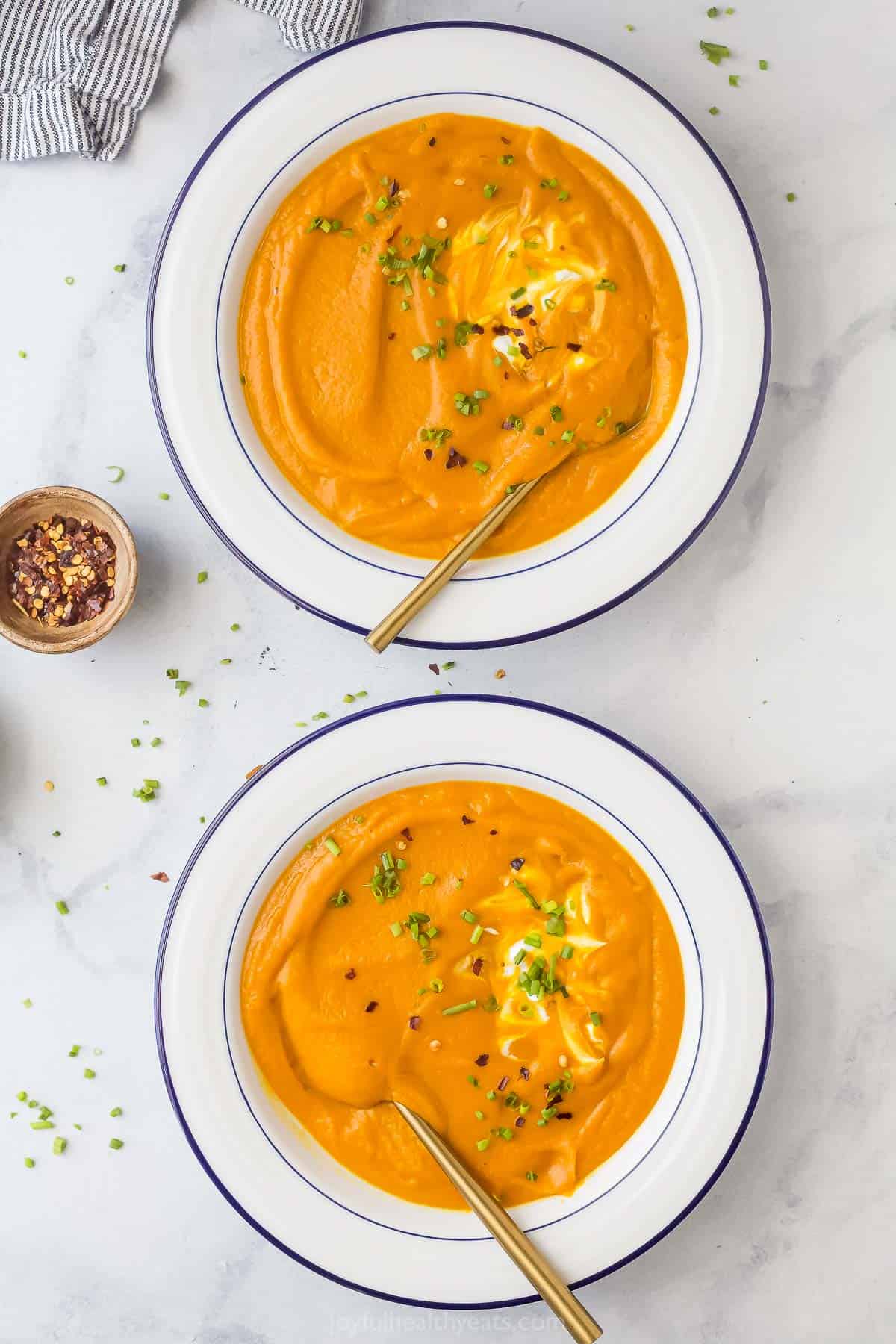 Two bowls of hearty carrot soup with spicy ginger. 