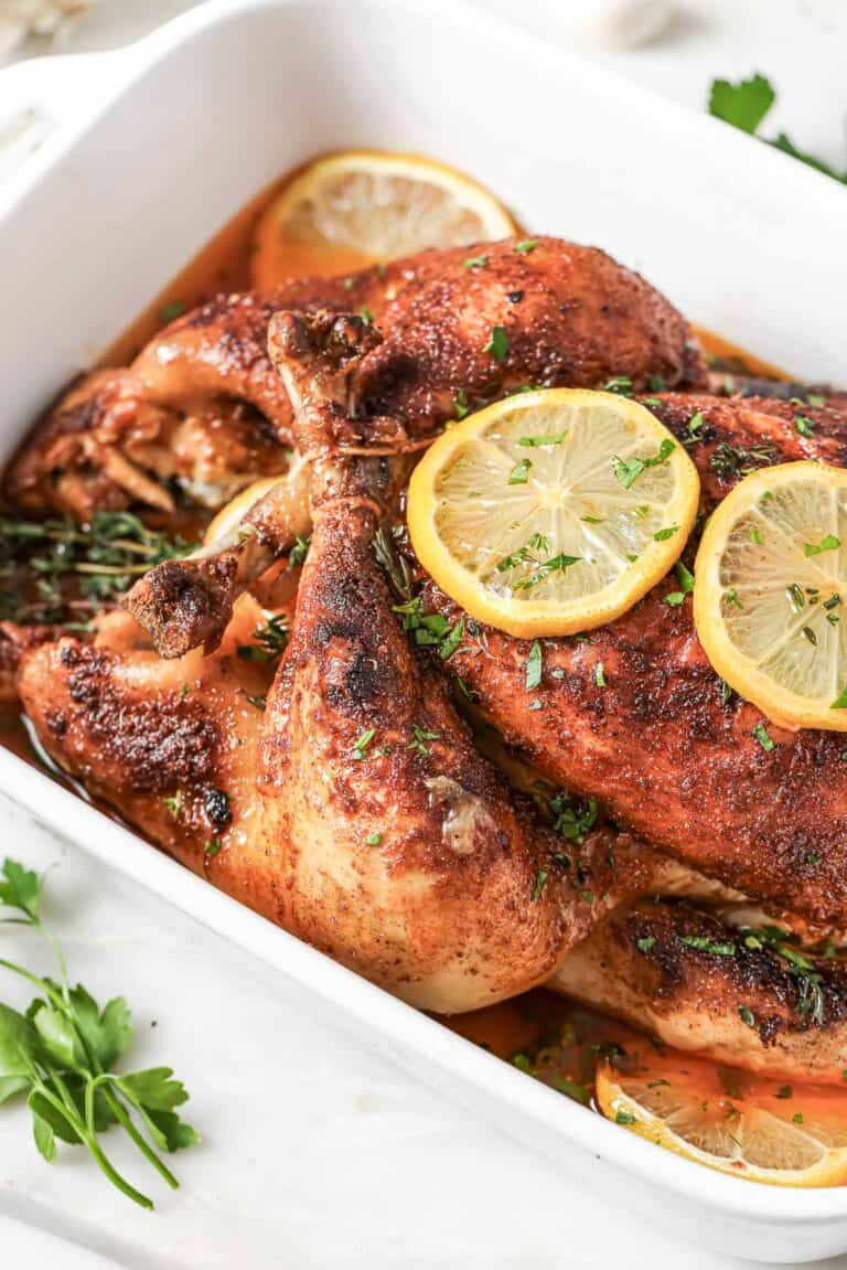 Angled photo of juicy, crockpot chicken with sliced lemons on top.