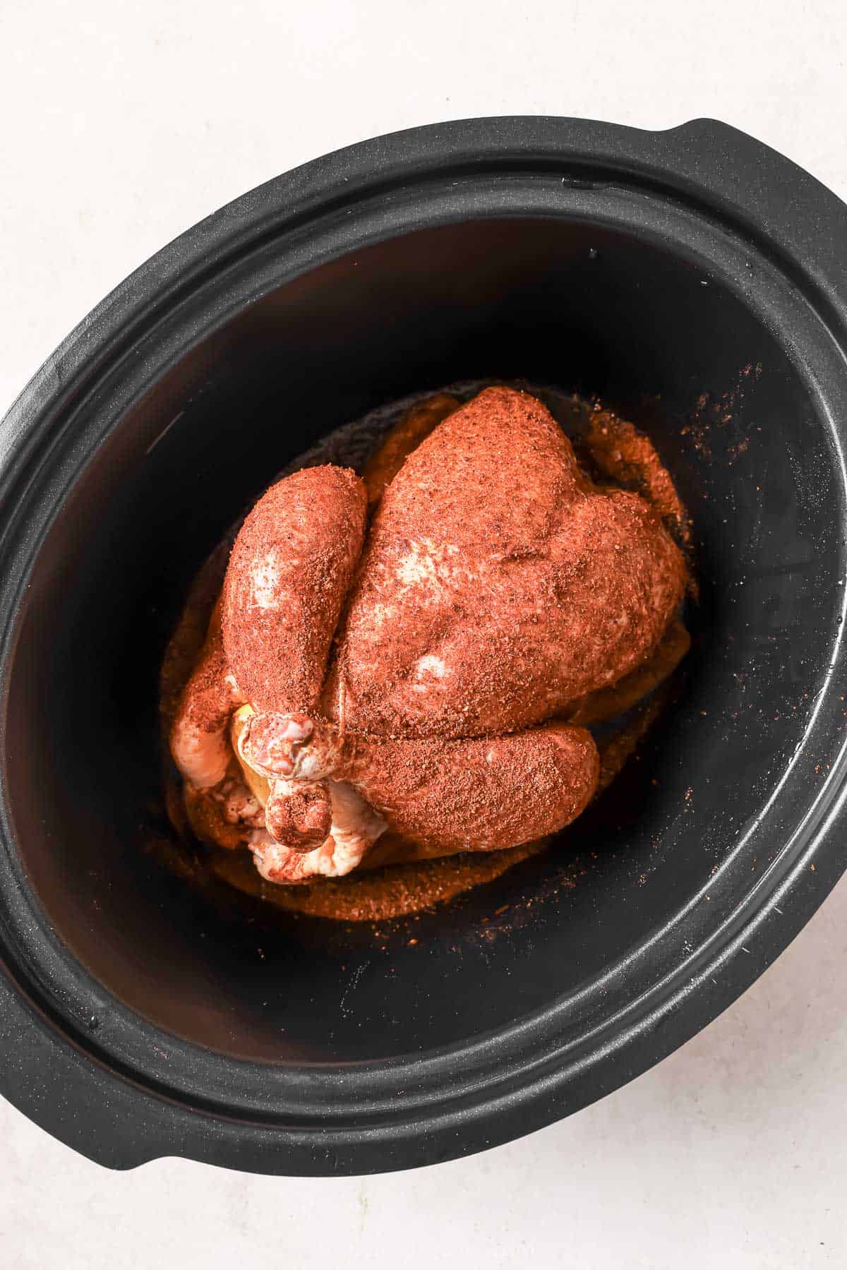 Rubbing the chicken with the spice mix and placing it in the crockpot.