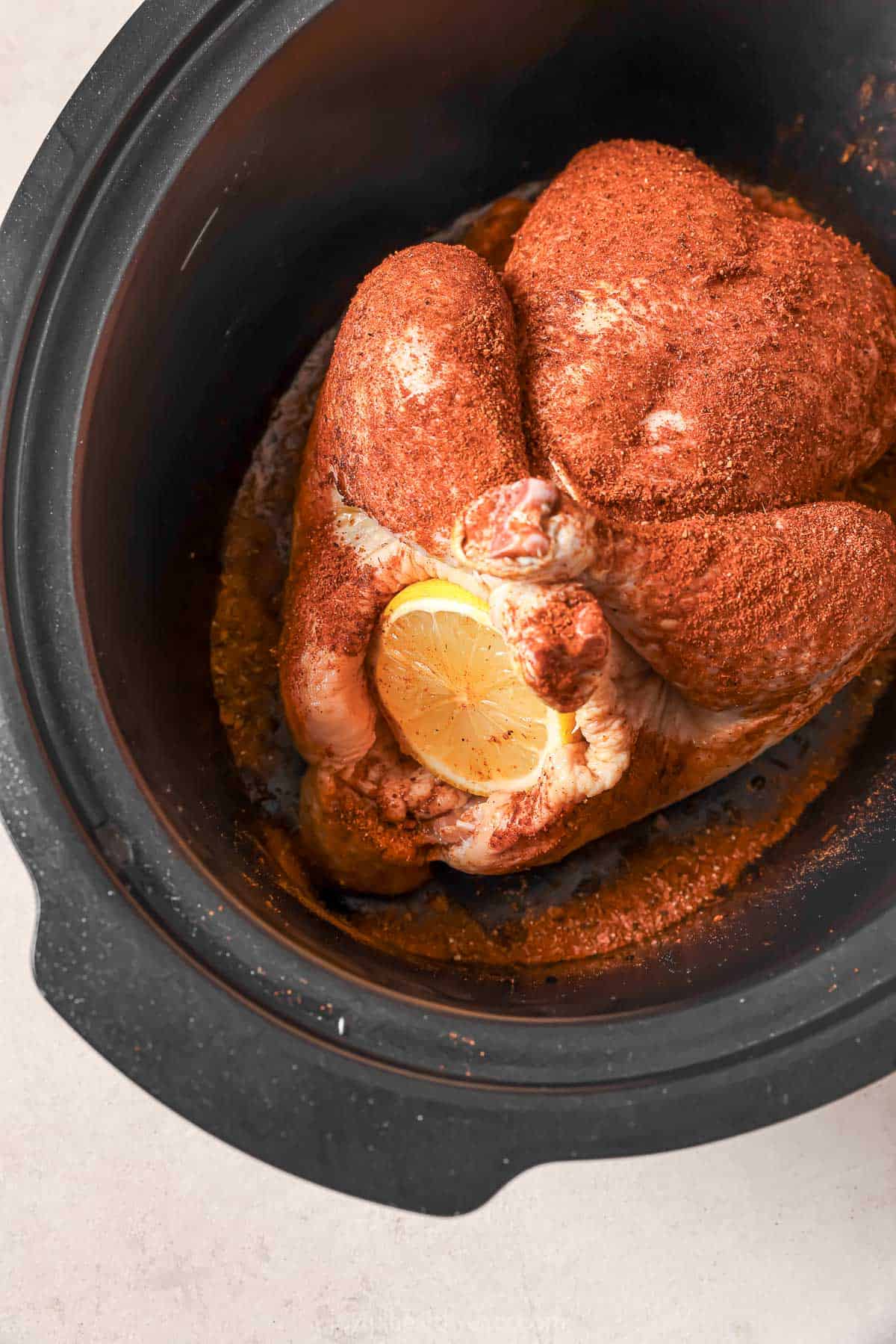 Cooked crockpot chicken with a slice of fresh lemon.