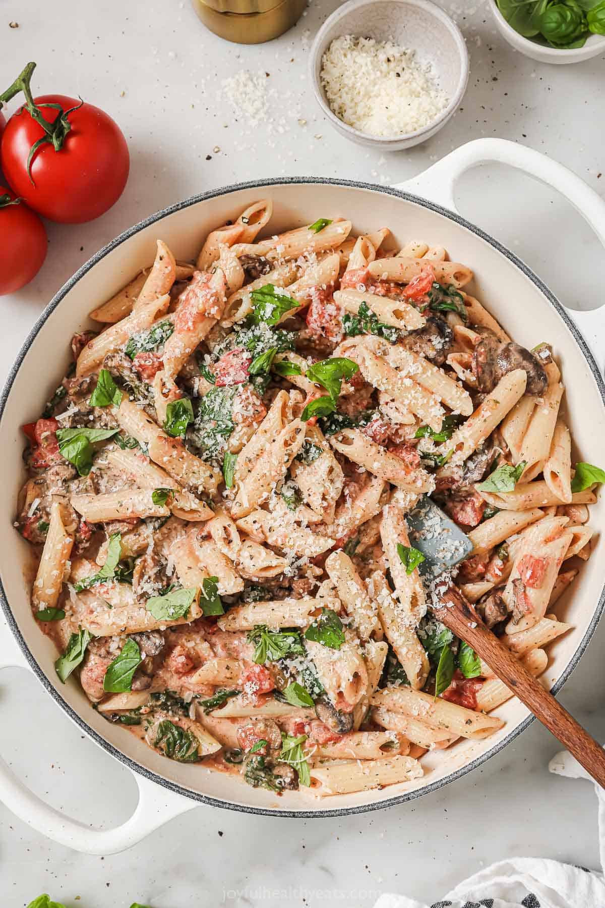 Skillet of creamy tomato-spinach mushroom pasta with Italian herbs. 