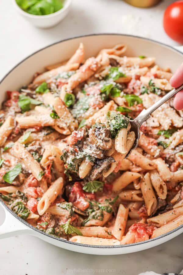 Grabbing some creamy spinach mushroom pasta with a fork.