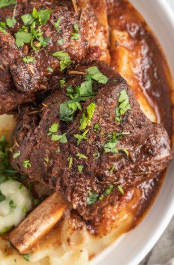 brasied balsamic short ribs plated with pureed potatoes and garnished with herbs