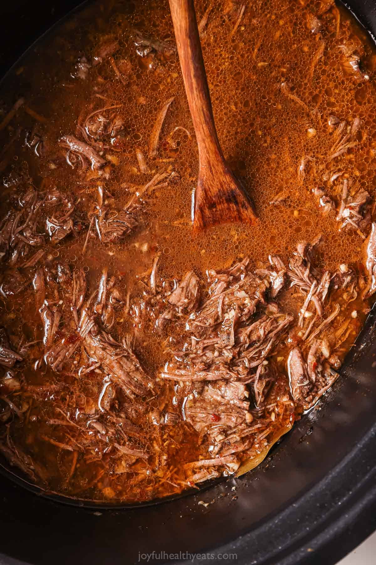 Returning the shredded beef to the crockpot. 