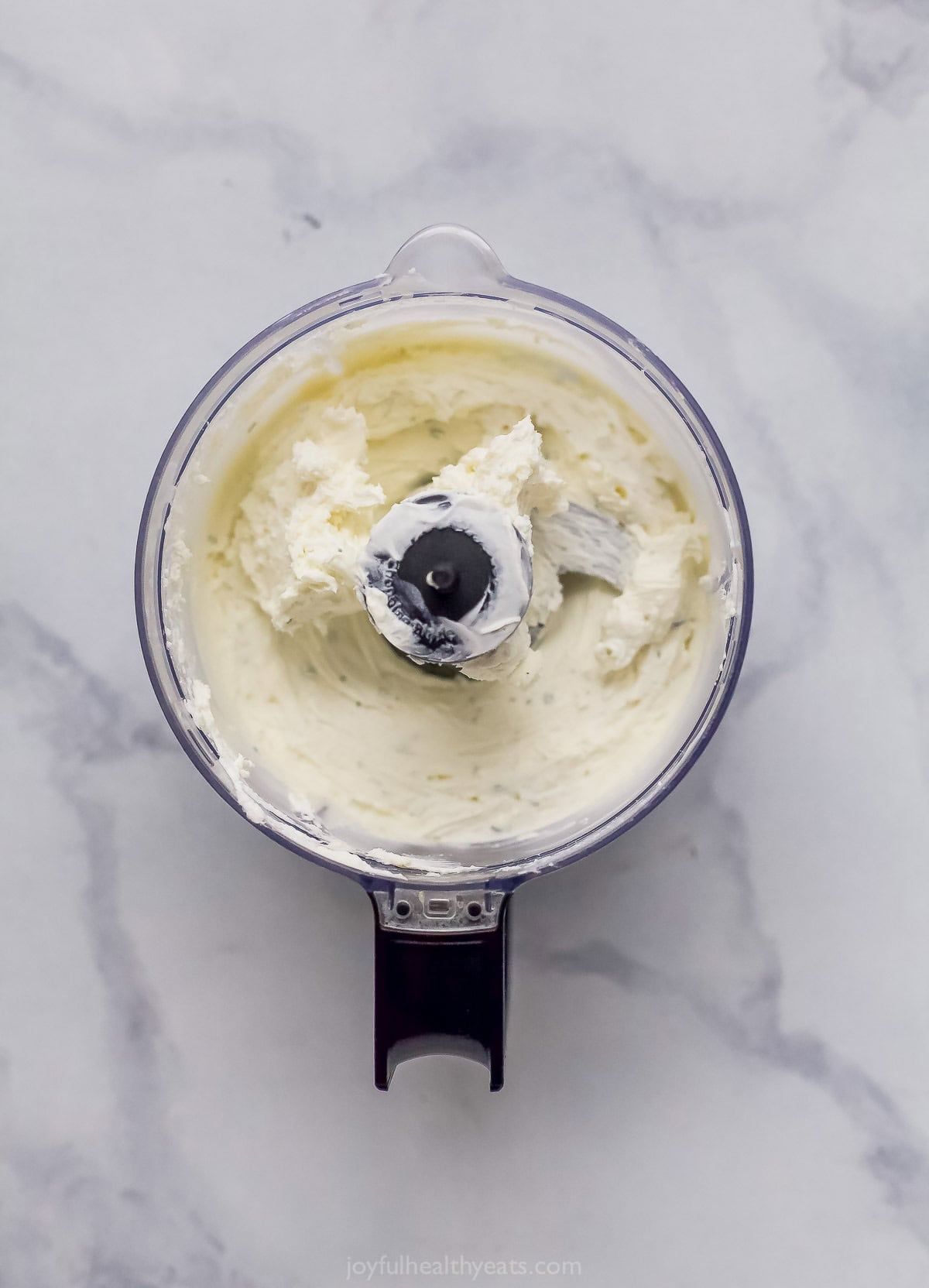 Overhead view of whipped goat cheese in food processor