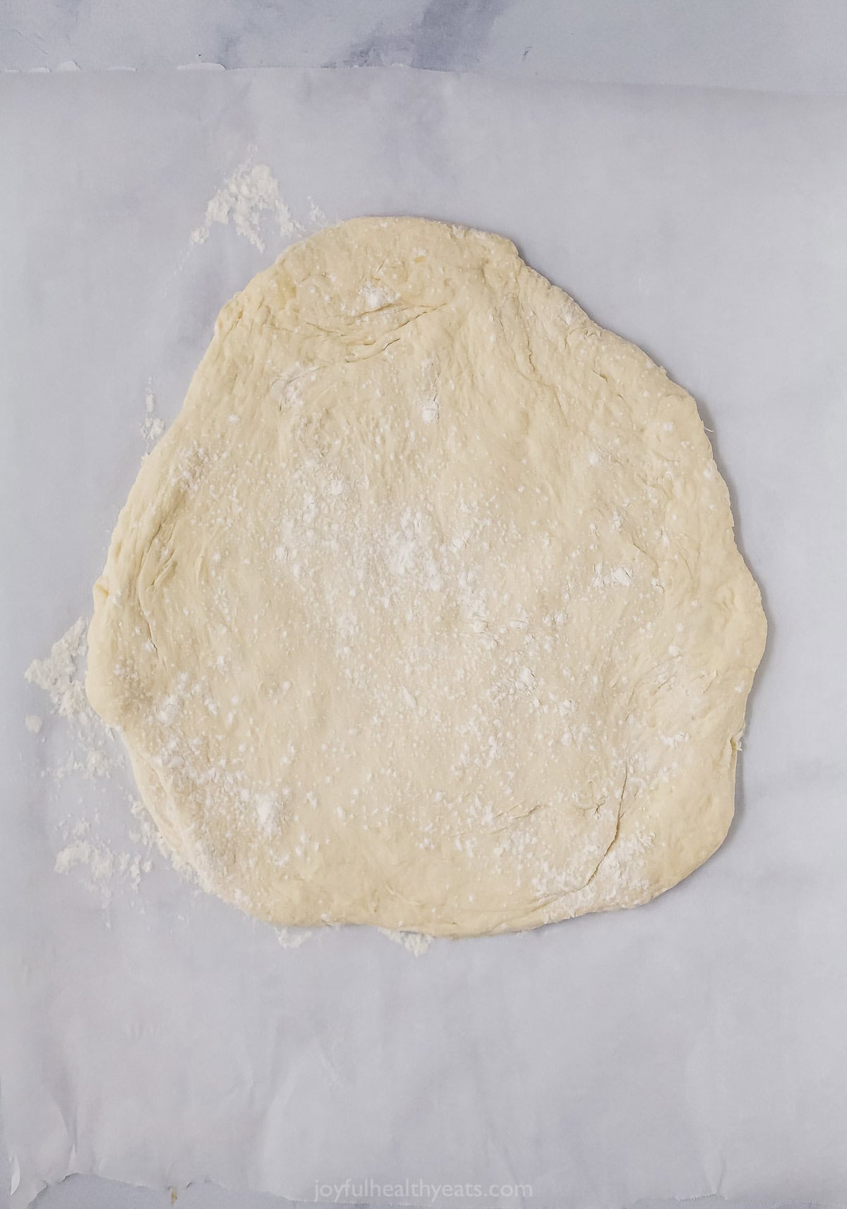 Roll out the pizza flour on the parchment paper