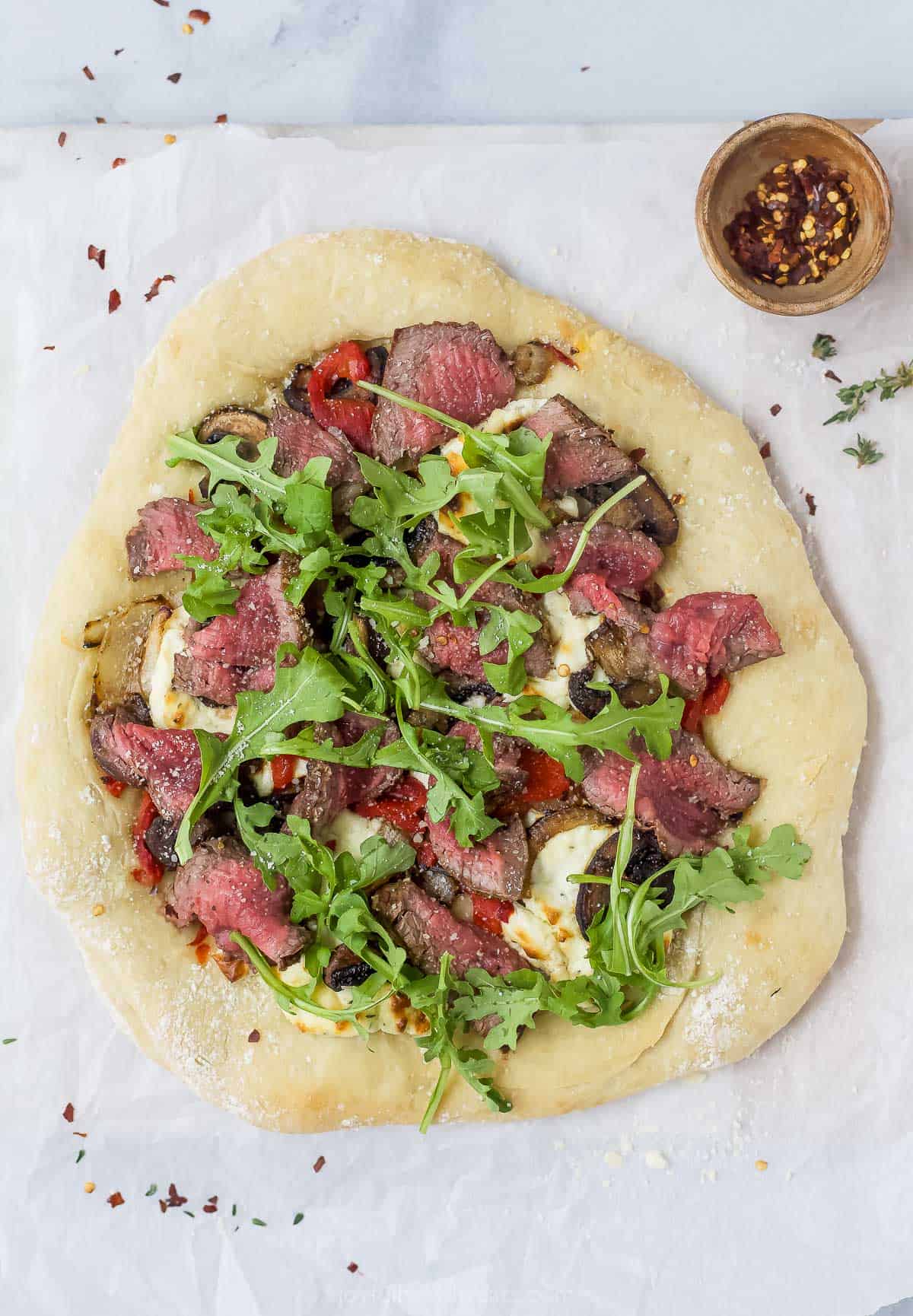 Overhead view of homemade steak pizza before slicing