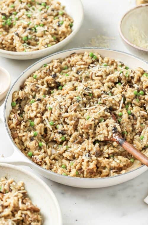 Wild mushroom risotto with chewy peas and parmesan cheese in a serving bowl.