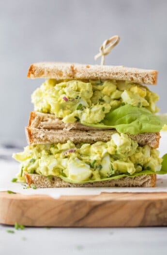 a stacked sandwich with bread, avocado egg salad and lettuce