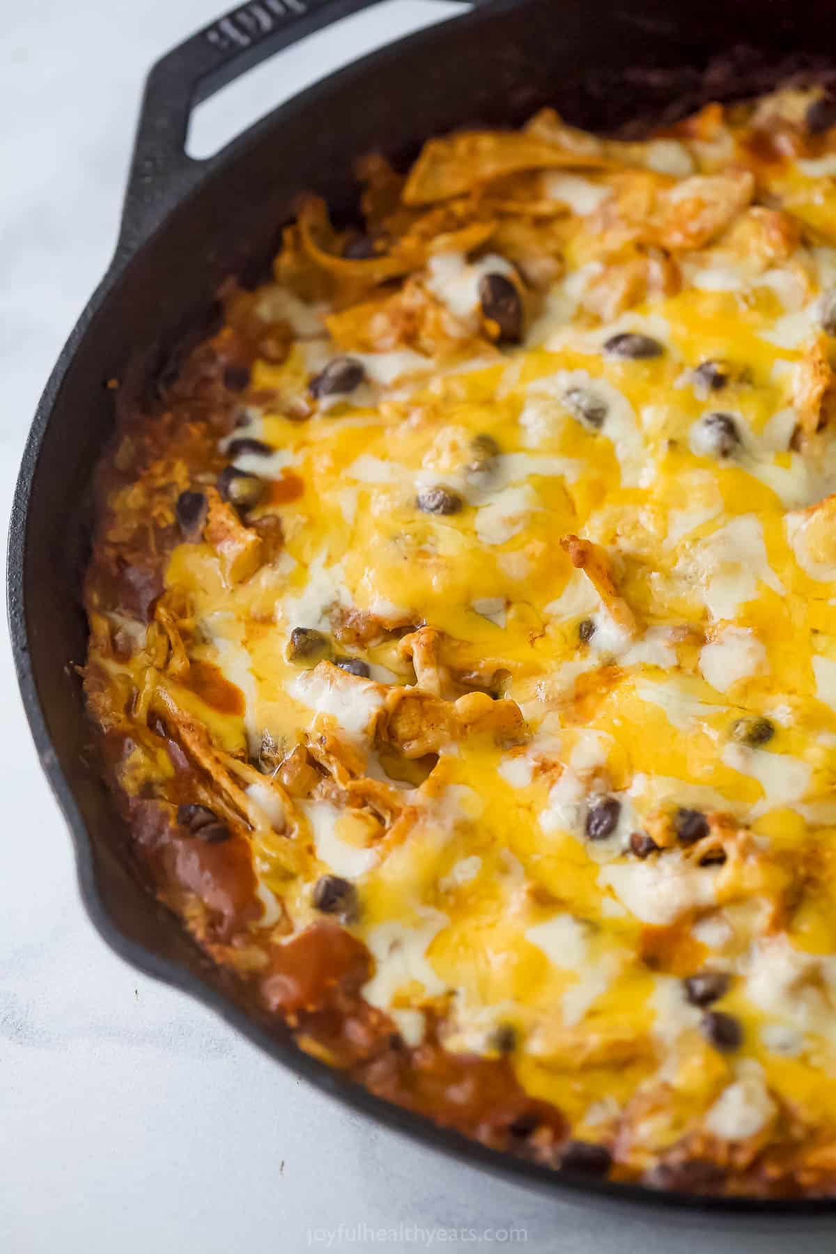 Angled image of cheesy chicken casserole in cast-iron skillet. 