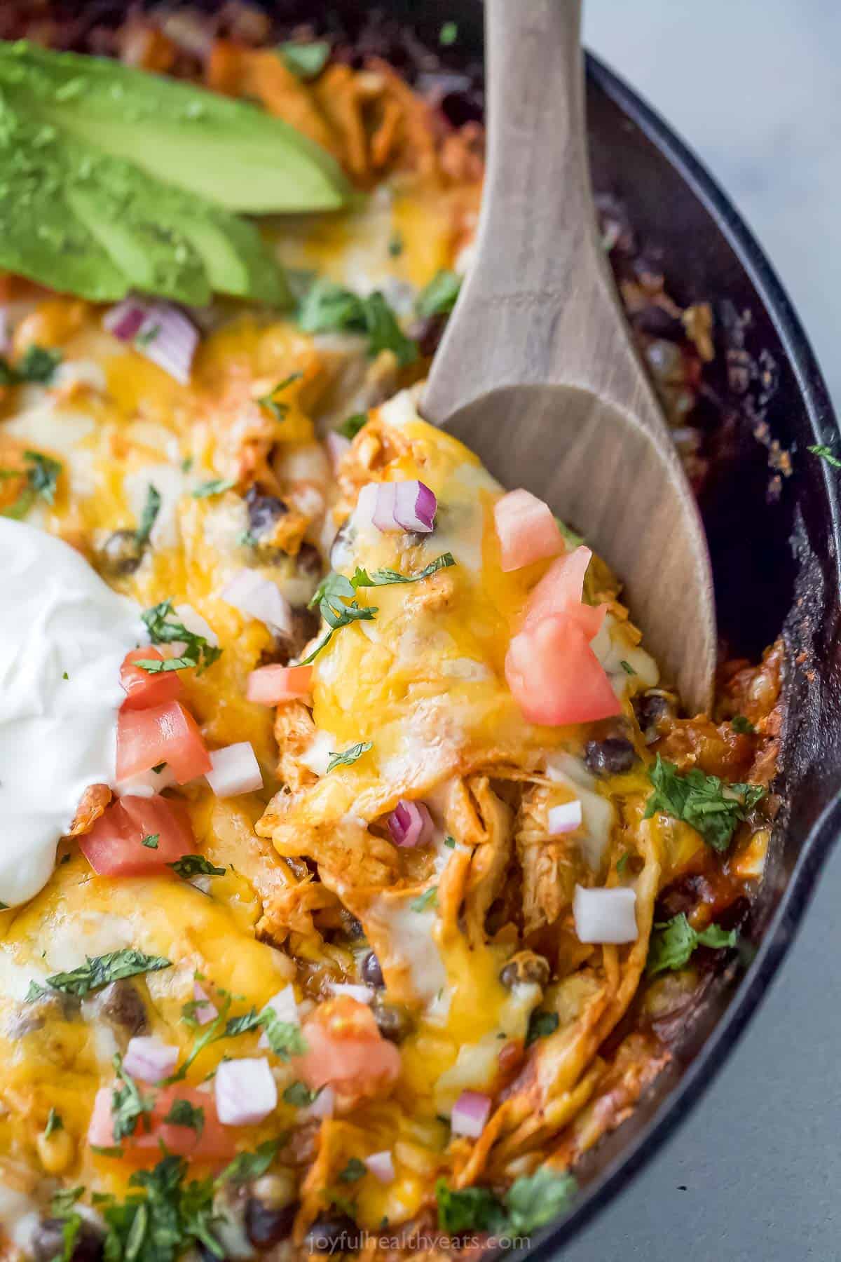 Spoonful of cheesy chicken casserole with pico de gallo, avocado, and sour cream. 