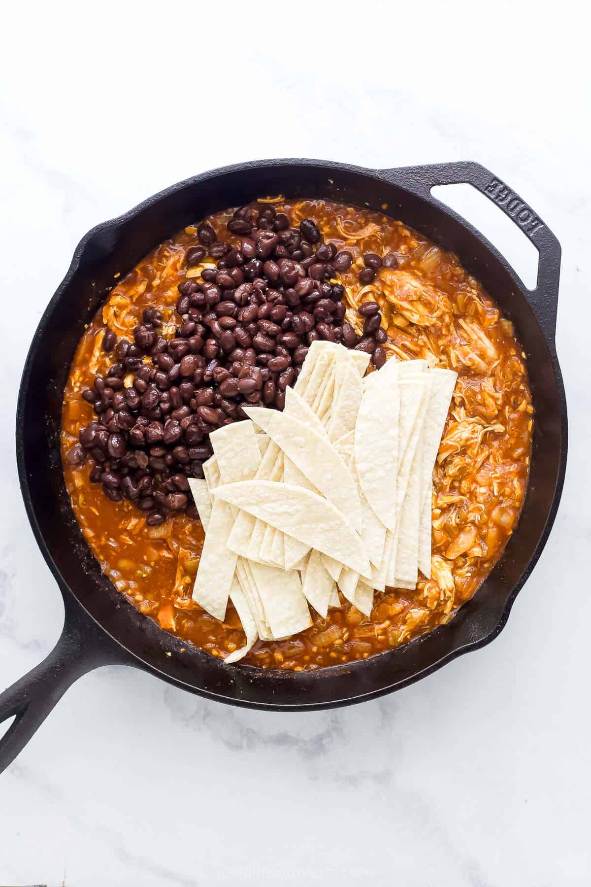 Adding tortillas and beans. 