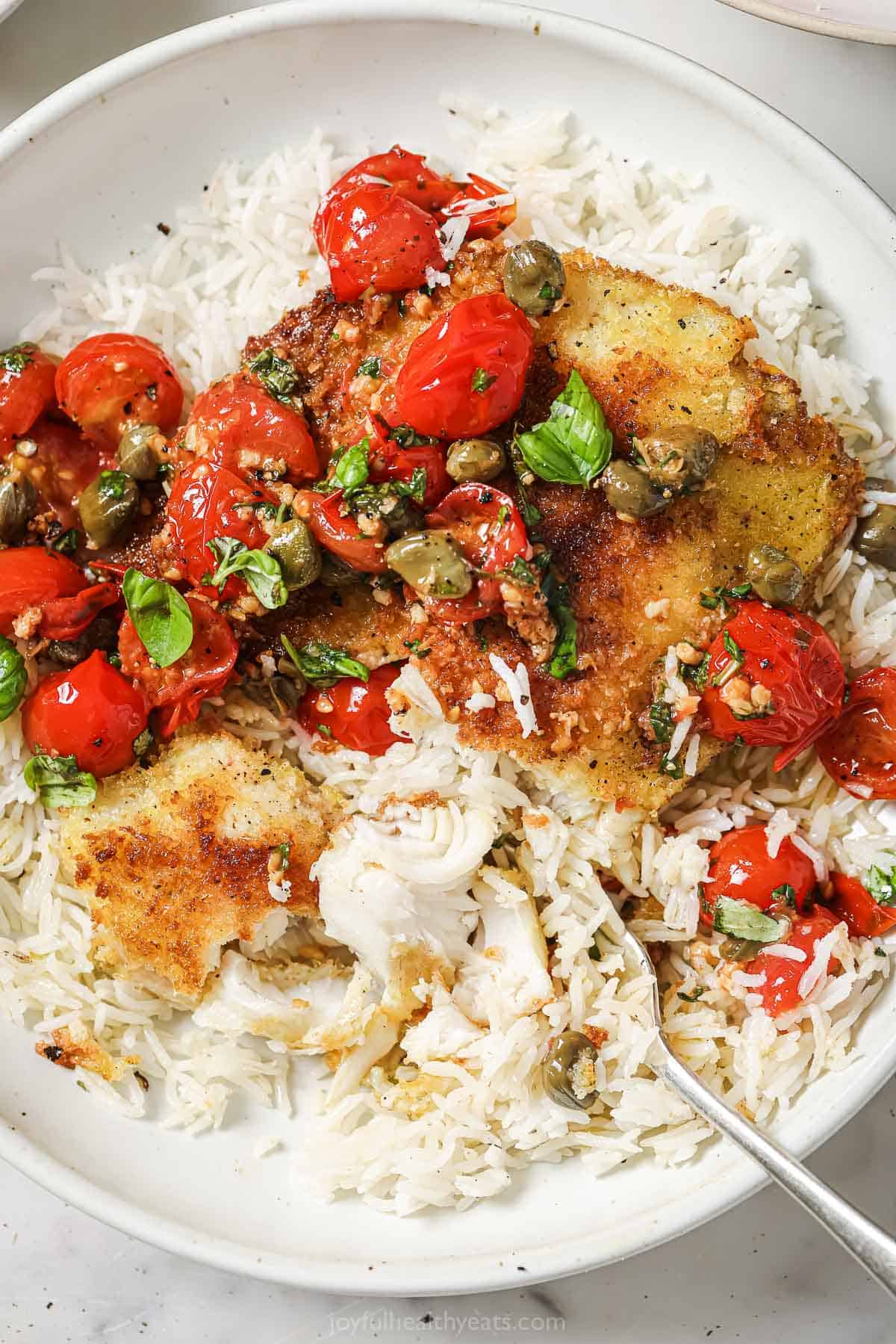 Grabbing some breaded fish with tomato-basil sauce and rice with a fork. 