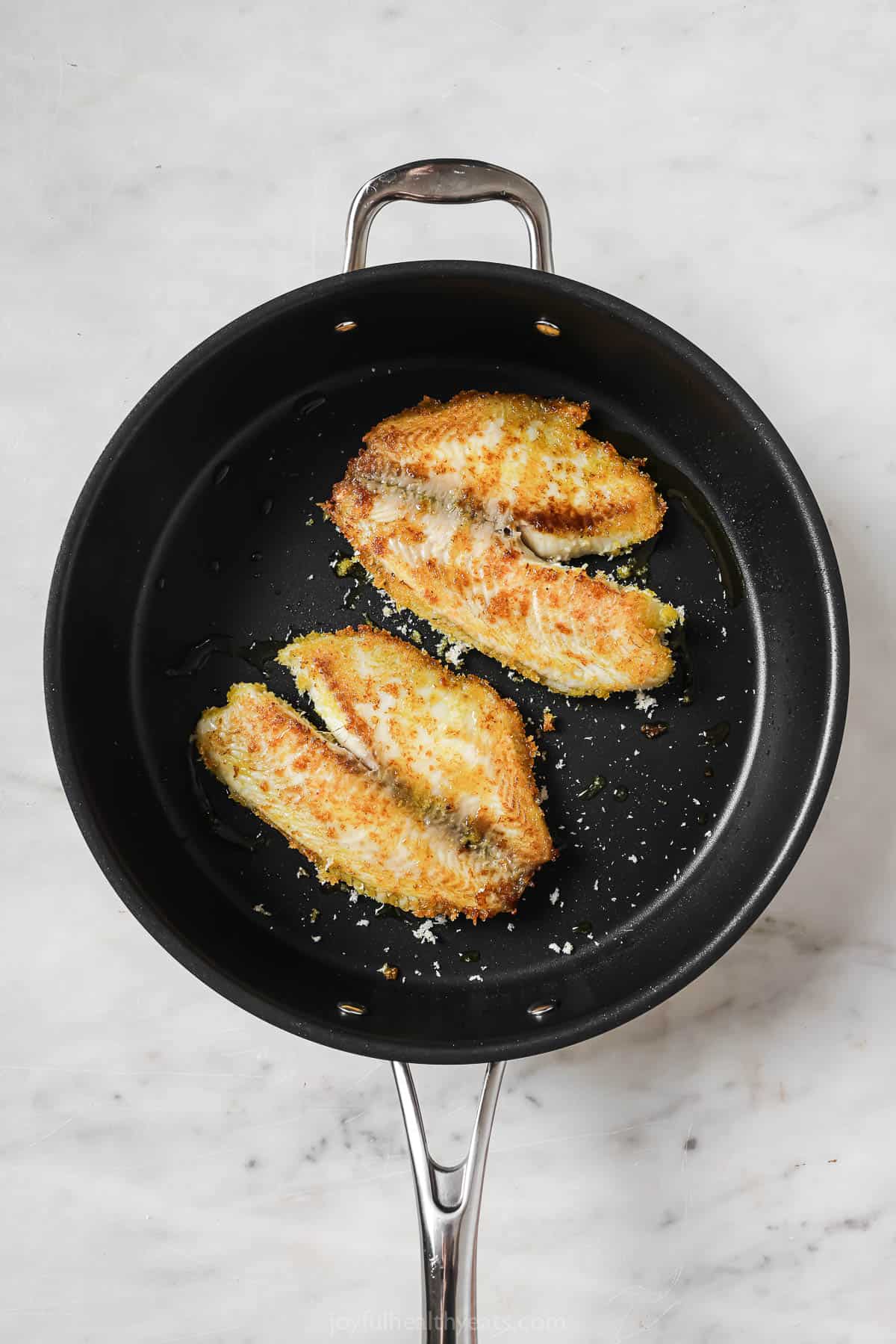 Pan-fried tilapia in the skillet.