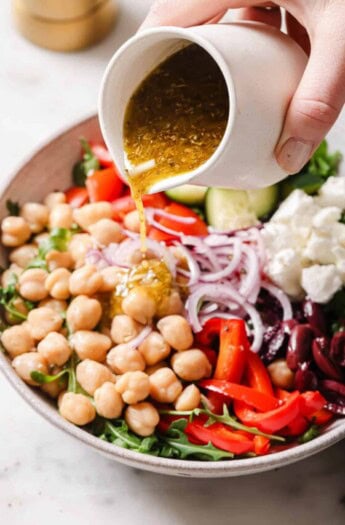 Pouring vinaigrette over the Mediterranean salad.