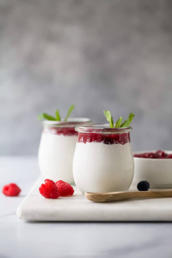 Coconut panna cotta in serving glasses with raspberry-blueberry compote.