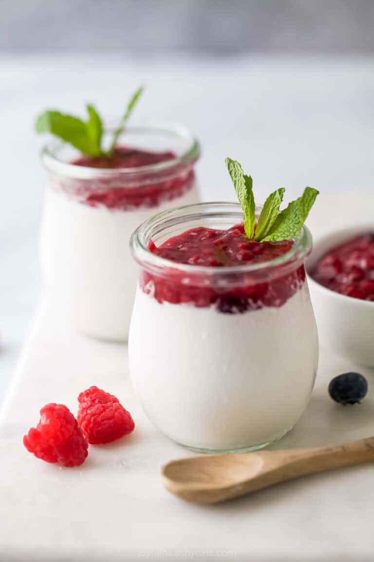 Silky coconut panna cotta with berry compote in crystal serving glasses.