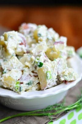 Un bol blanco de ensalada de patatas a las hierbas con parmesano