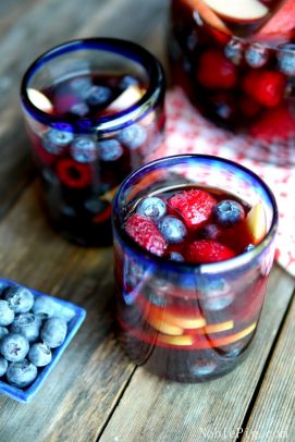 Sangría roja blanca y azul y fruta en un vaso con hielo