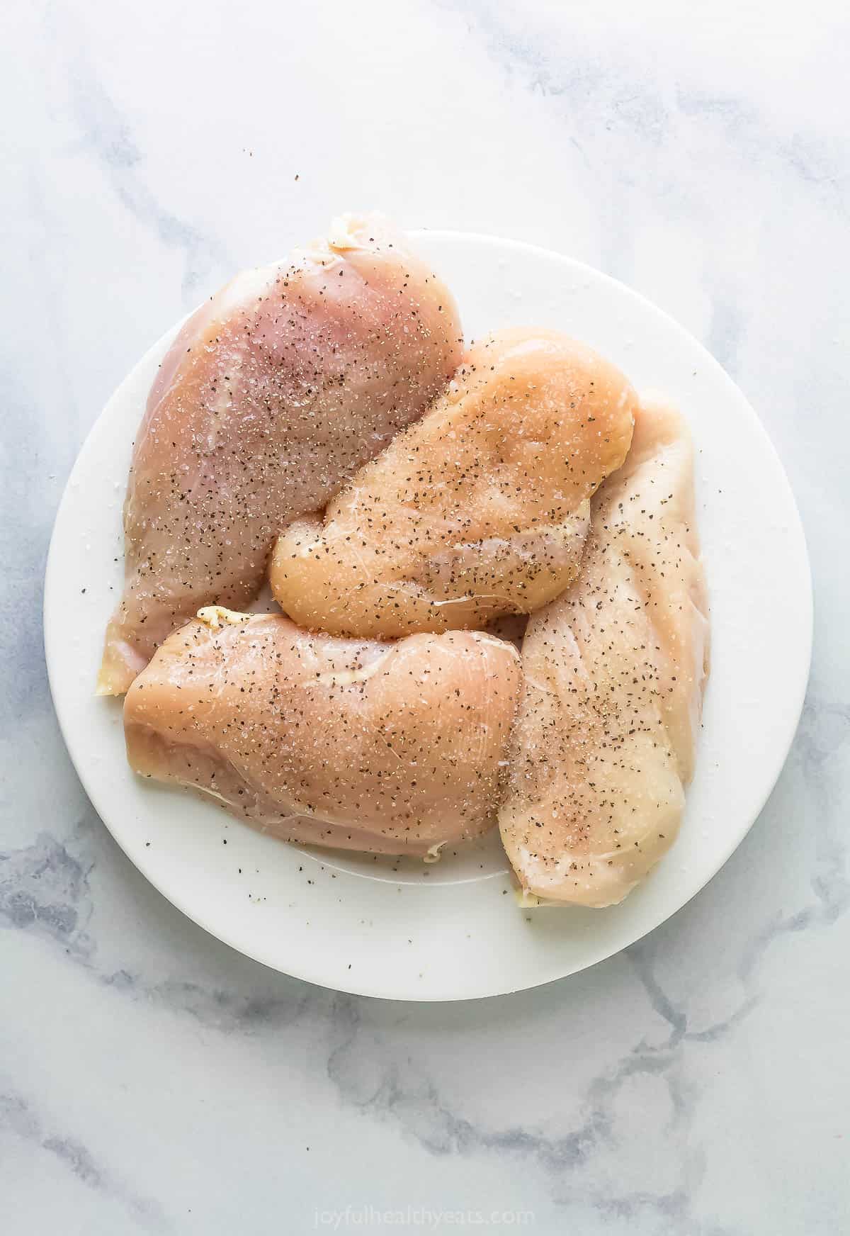 Raw chicken seasoned with salt and pepper. 