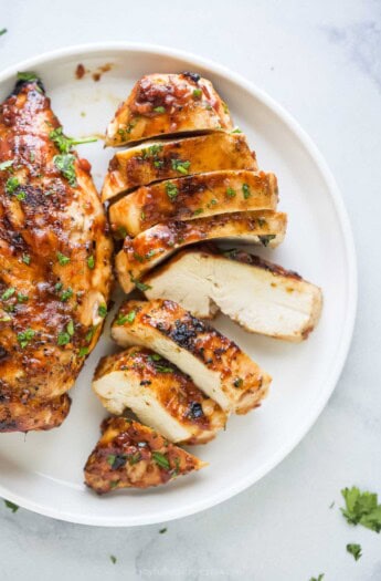 Juicy, sliced grilled chicken on a serving plate.