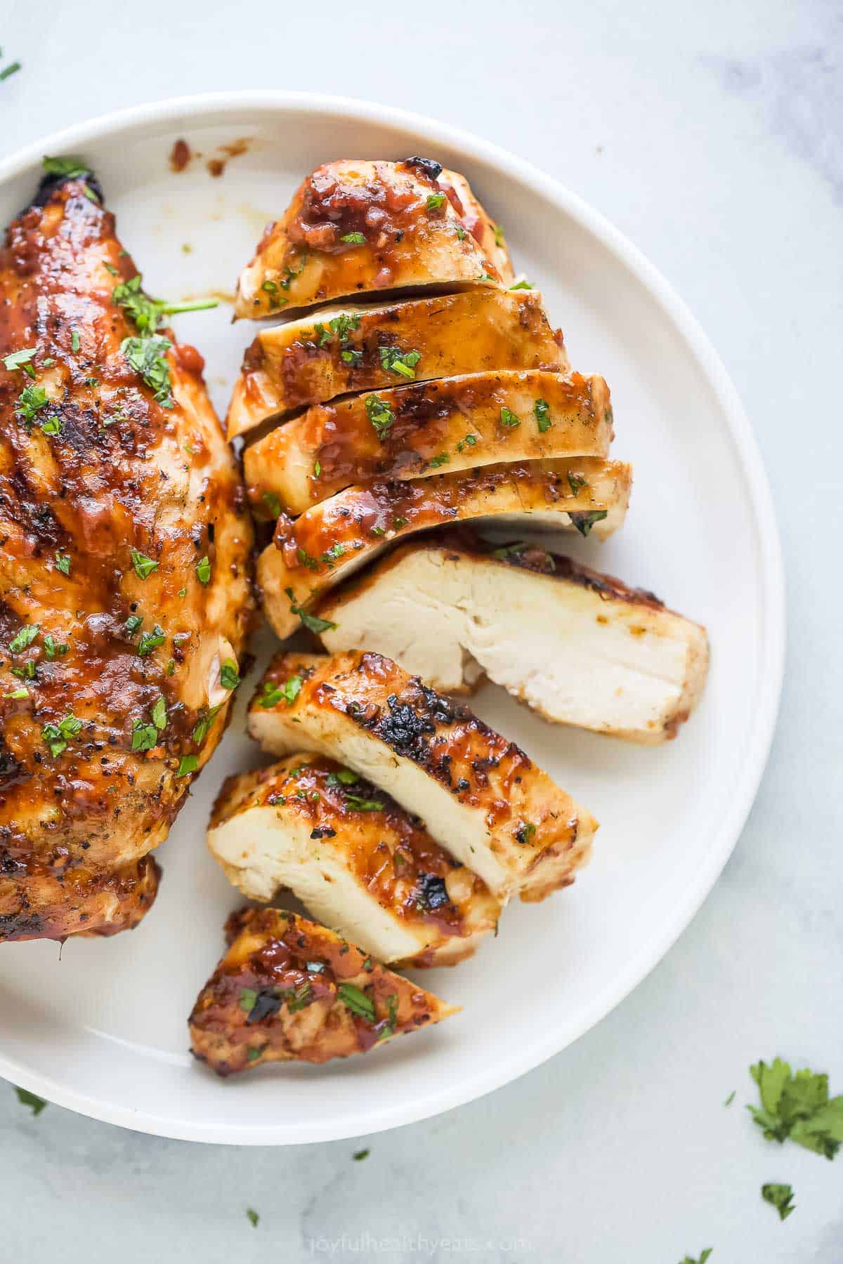 Juicy, sliced grilled chicken on a serving plate. 