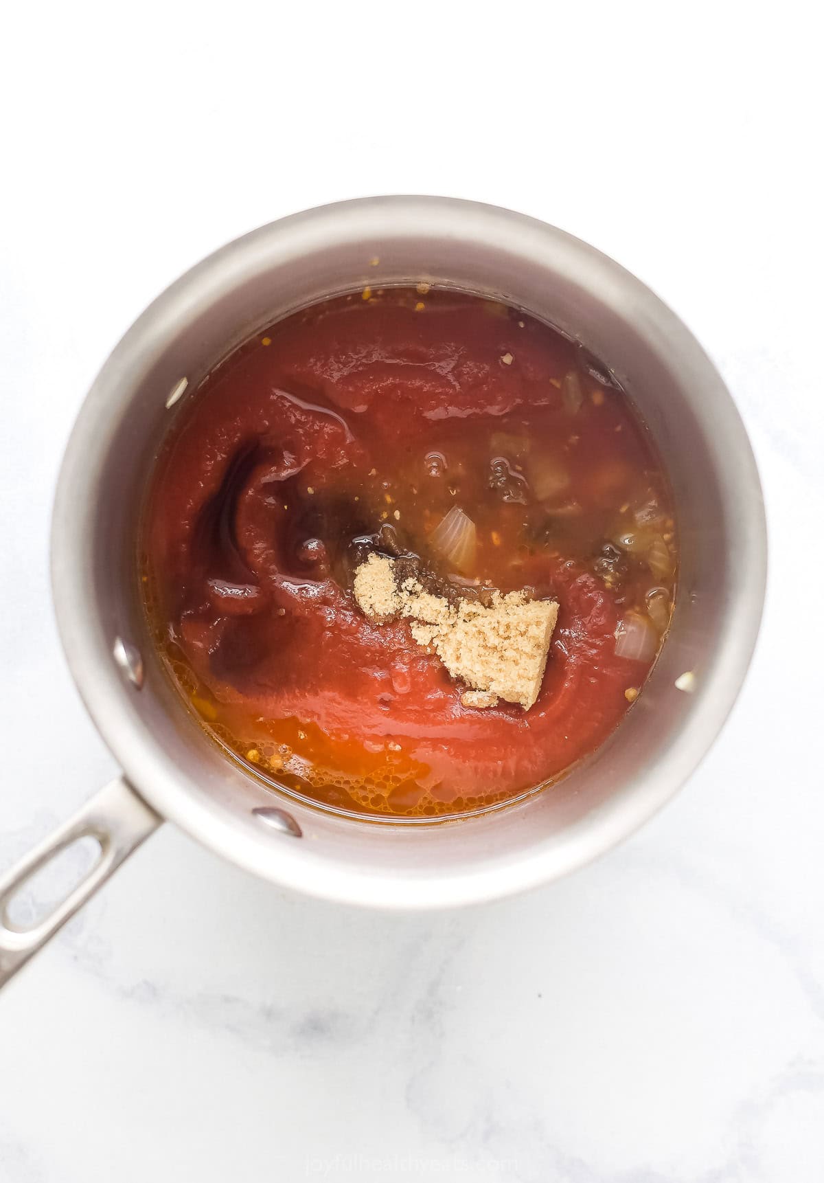 Adding the tomato sauce, vinegar, brown sugar, and liquid smoke to the chipotle-onion mixture. 