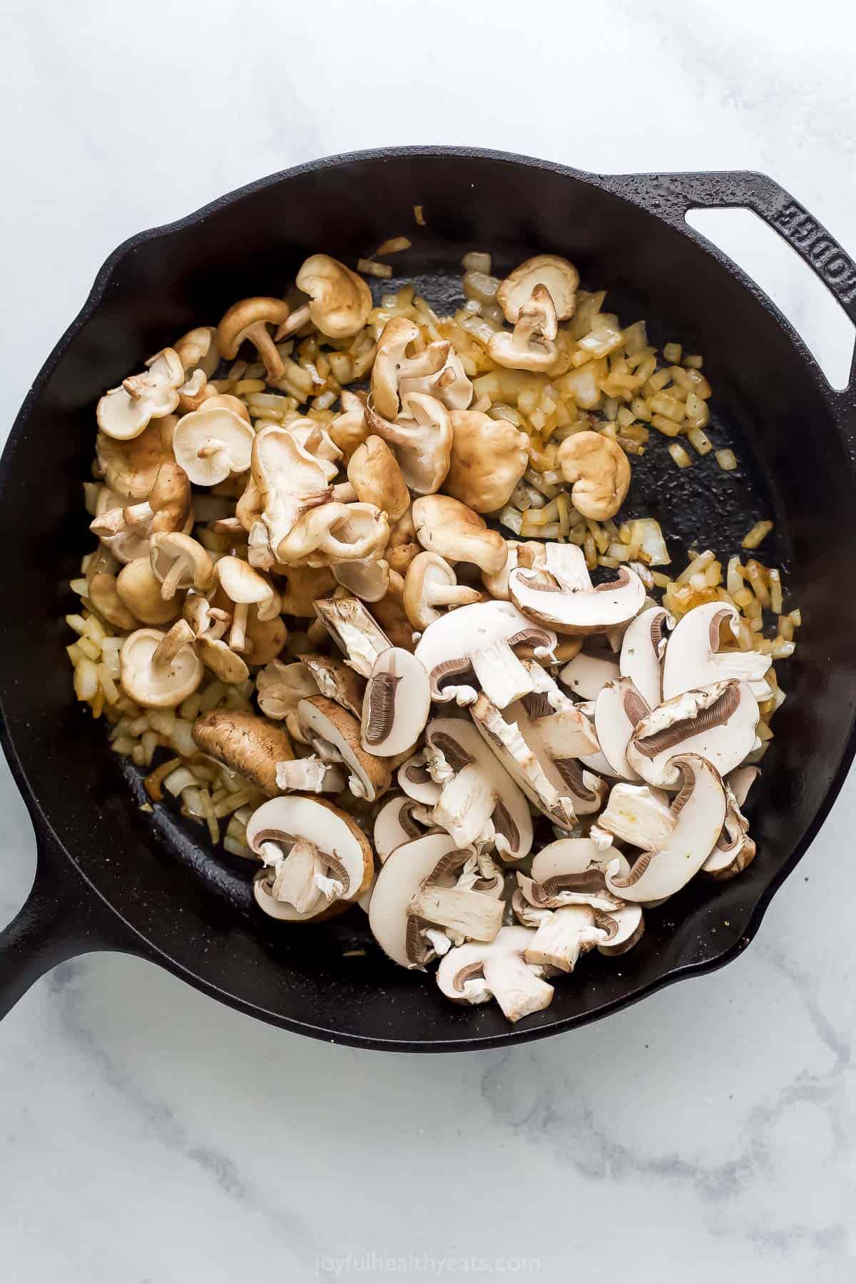 Sautéeing the mushrooms in the skillet with cooked onions. 