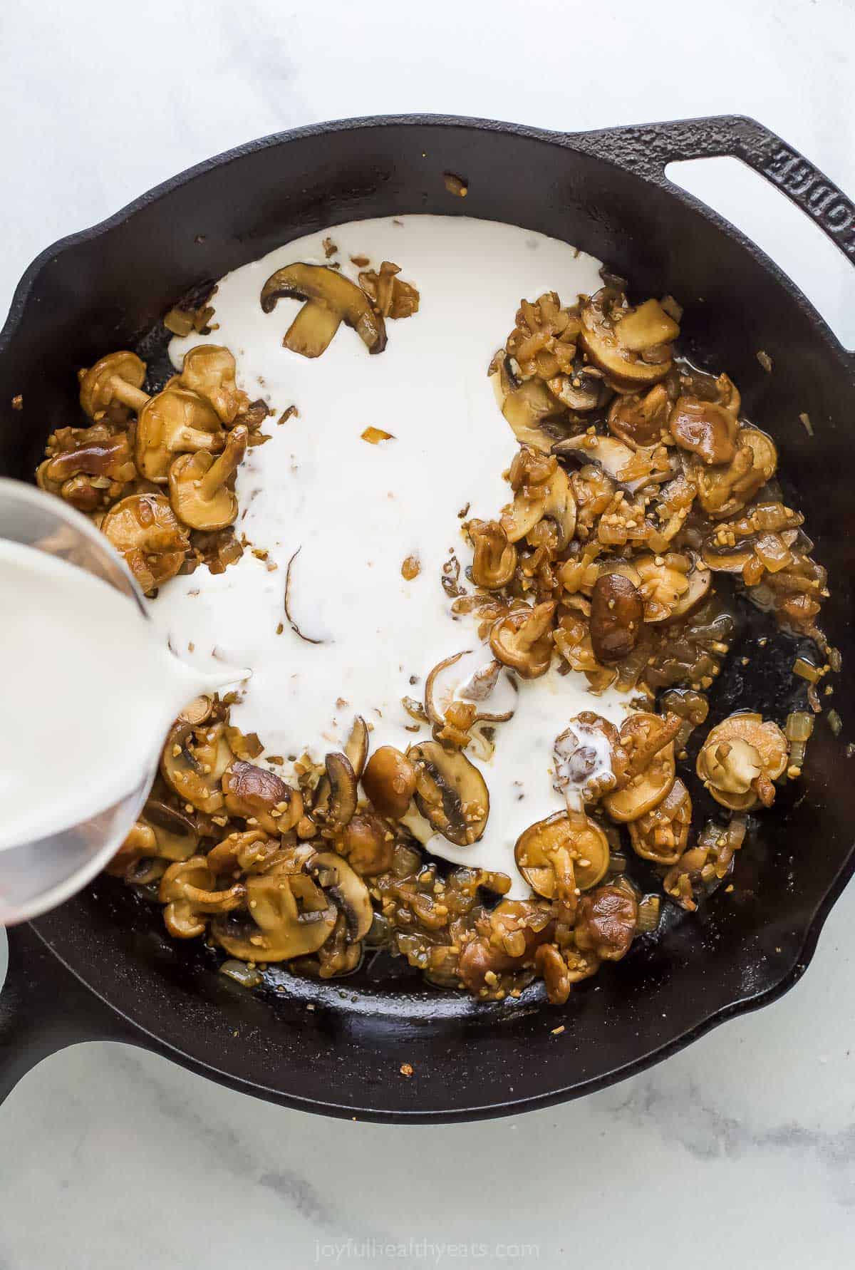 Pouring coconut cream into the skillet to make the sauce. 