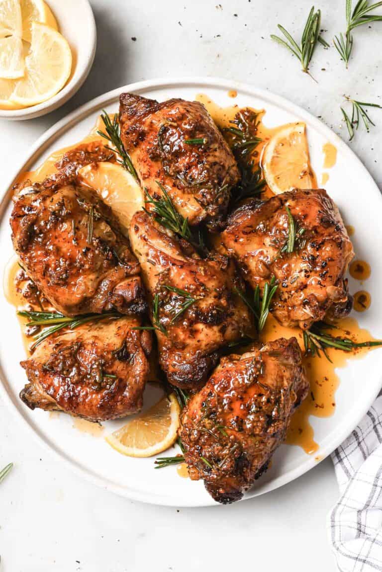 Juicy lemon rosemary chicken with cooking juices on a serving plate.