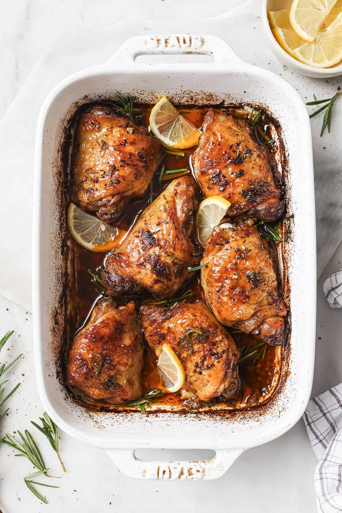 Freshly-baked chicken with herby rosemary and lemon juice in the baking dish. 